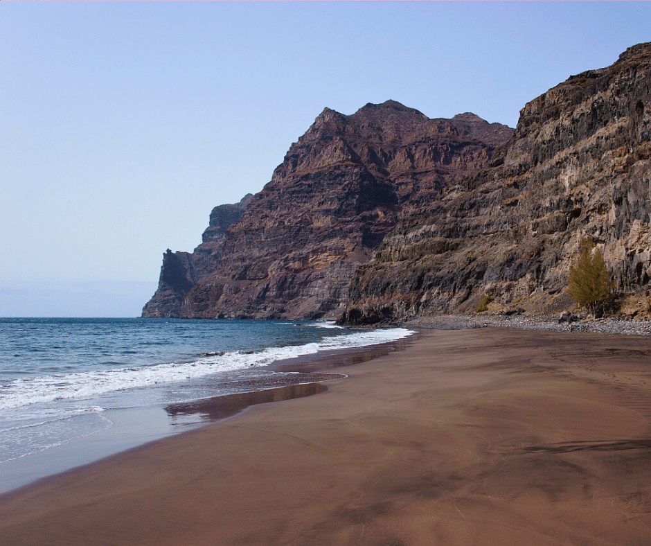 Güigüí wild black-sand cove framed by sheer volcanic cliffs, remote shoreline and Atlantic swells, La Aldea, west Gran Canaria.