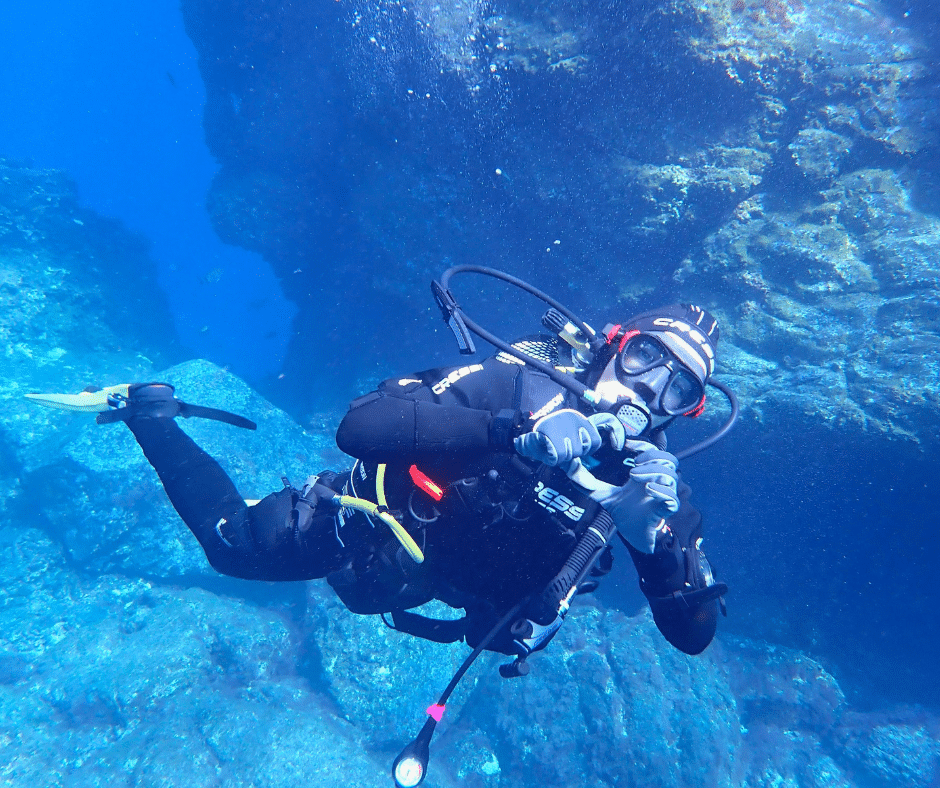 Scuba diver over volcanic reef at El Cabrón (Arinaga), shoals of roncadores and lava arches in clear Atlantic water, Gran Canaria.